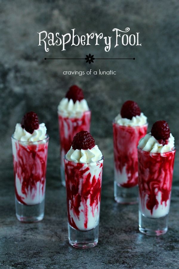 raspberry trifle with whipped cream and strawberries in shot glasses on table