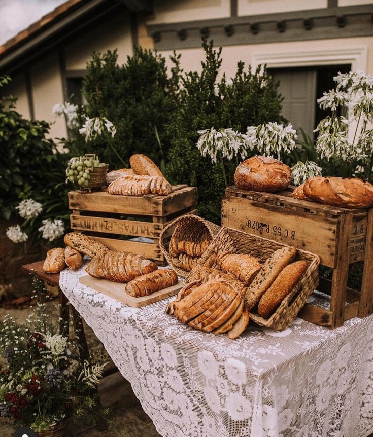 breads and pastries are displayed on a table outside in front of a house