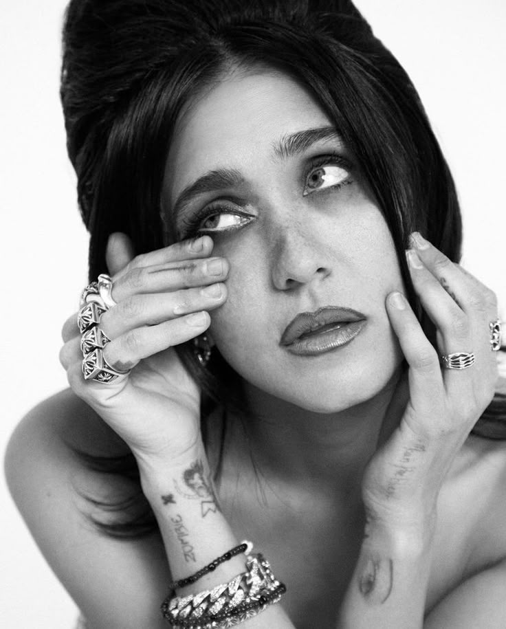 black and white photograph of a woman with tattoos holding her hands up to her face