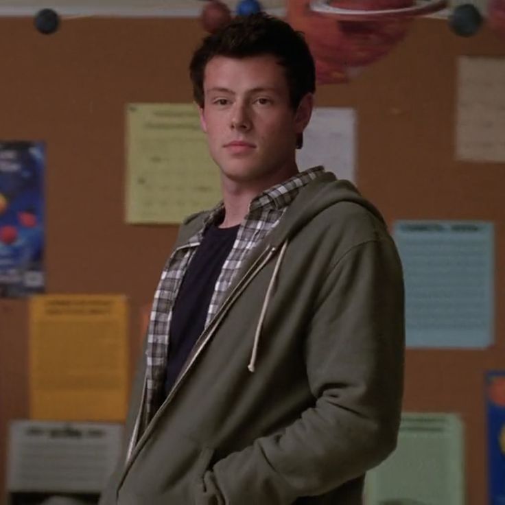 a young man standing in front of a bulletin board