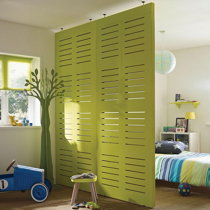 a child's bedroom decorated in green and blue with a tree on the wall