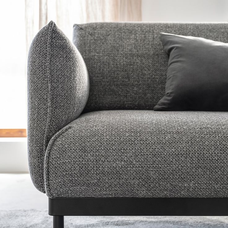 a gray couch with two black pillows on it