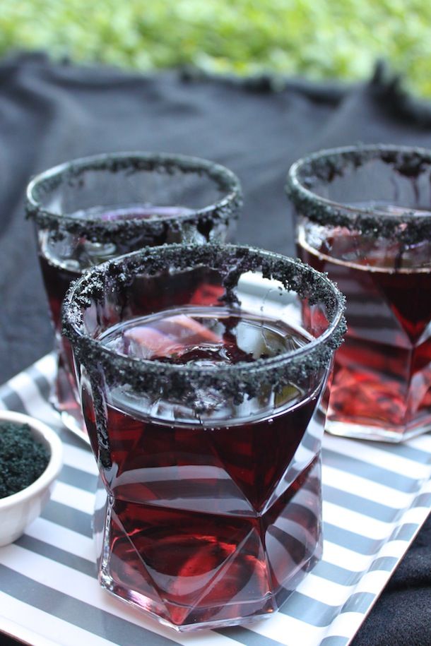 three glasses filled with liquid sitting on top of a white and gray tray next to a bowl