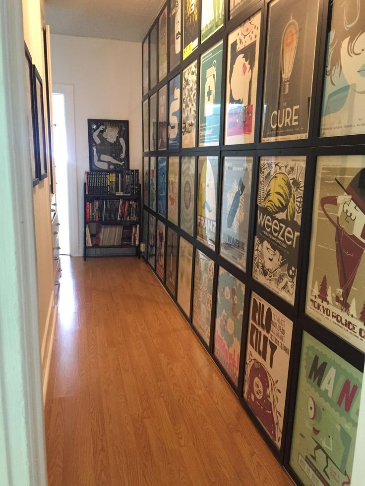 a hallway with posters on the wall and wooden flooring in front of an open door