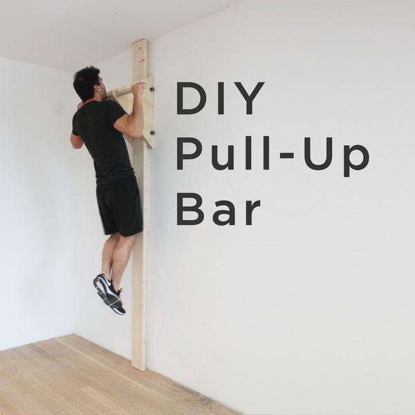 a man climbing up the side of a wall with his feet on a wooden bar