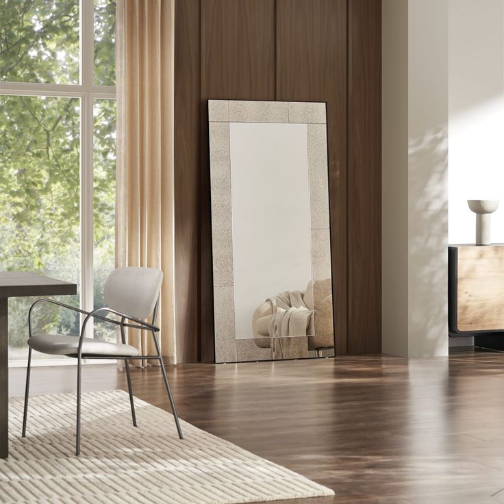 a large mirror sitting on top of a wooden floor next to a chair and table