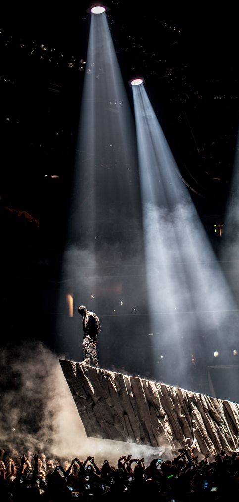 a man standing on top of a stone structure in front of some spotlights at a concert