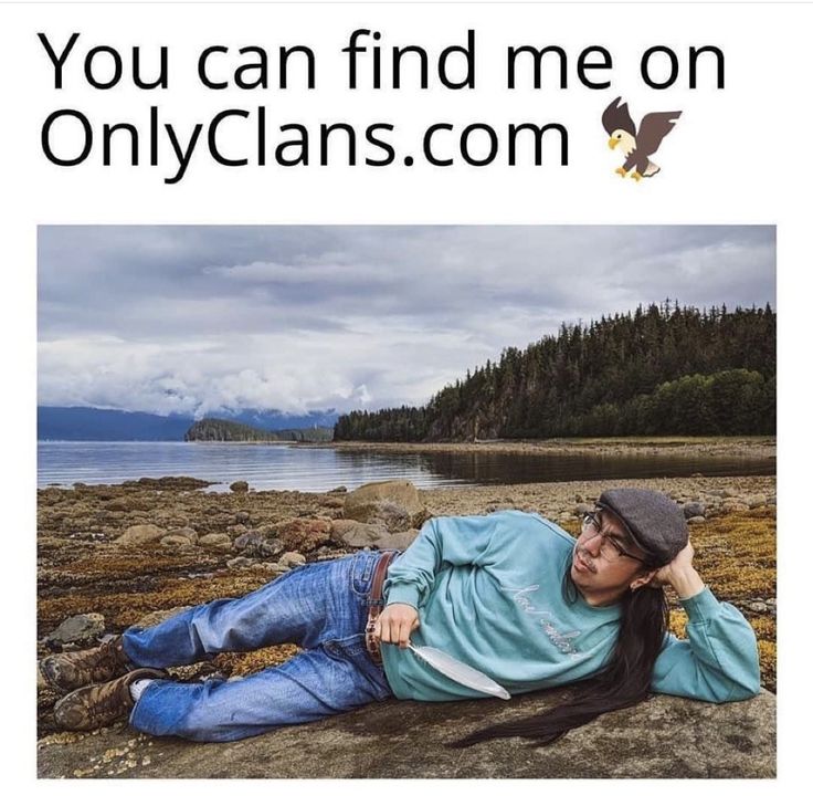 a woman laying on top of a rocky beach next to the ocean with an eagle flying over her head