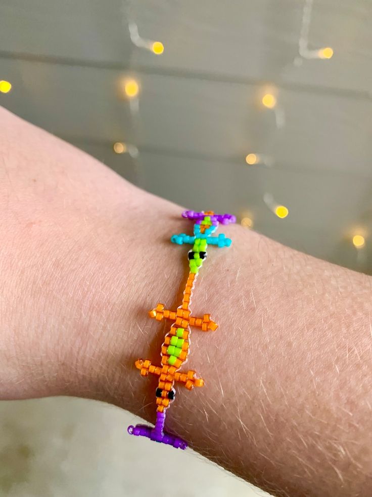 a person's arm with a colorful beaded bracelet on it and lights in the background