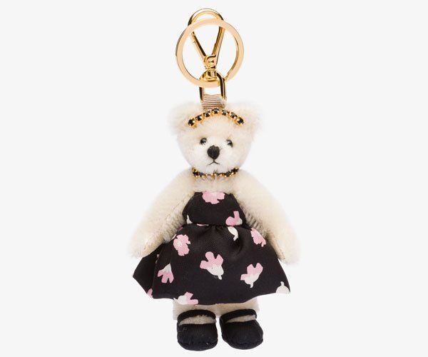 a white teddy bear wearing a black dress with pink flowers on it's chest