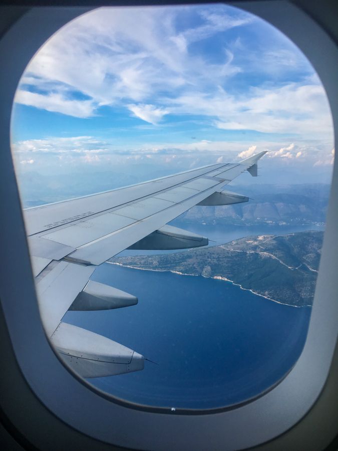 the view from an airplane window looking out on water and land below it, with mountains in the distance