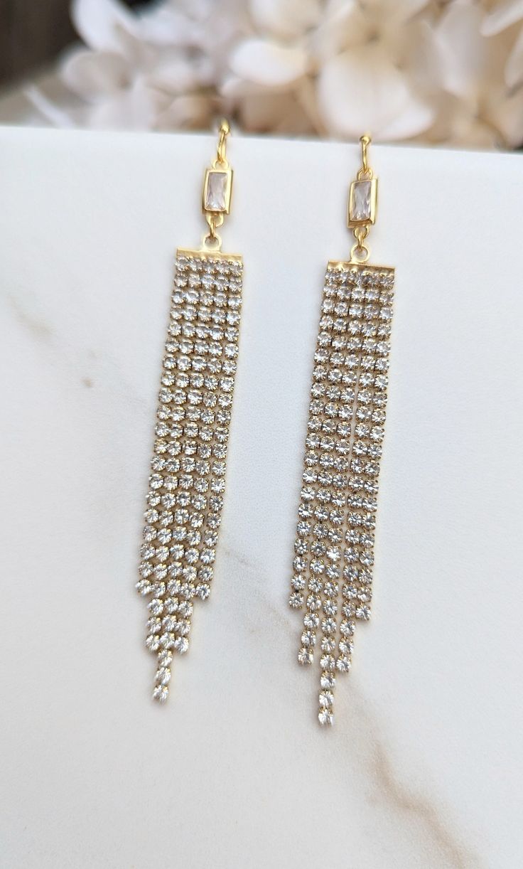 Long Gold Rhinestone Chain Fringe Earrings, Gold Faceted Rectangle Connector, Rhinestone Tassel, Fringe Statement Earrings, Crystal Fringe These eye-catching crystal rhinestone earrings will make you look and feel special. They feature a beautiful gold-plated glass crystal rectangle connector with five strands of rhinestone fringe that add a little glamour and glitz.  Gold plated circular micro pave/rhinestone posts. Length - 3 inches  Drop Length - 2.75 inches Width - .5 inches Gold Rectangular Crystal Earrings For Party, Elegant Dangle Rhinestone Fringe Jewelry, Elegant Rhinestone Fringe Dangle Tassel Earrings, Gold Metal Jewelry With Rhinestone Fringe, Gold Crystal Earrings With Rhinestone Fringe, Evening Jewelry: Rhinestone Fringe Drop Earrings, Chain Fringe, Gold Rhinestone, Rhinestone Earrings