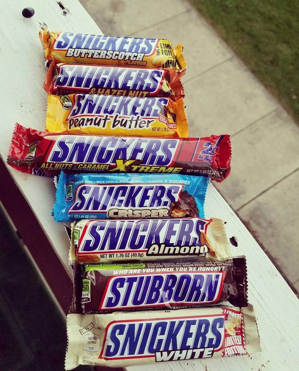 five bars of snickkers sitting on top of a white bench