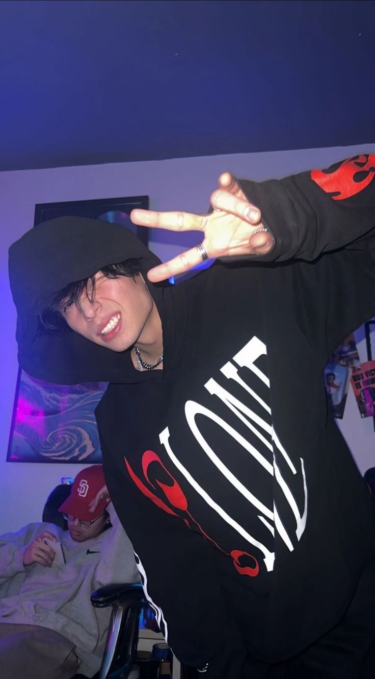 a young man making the peace sign with his hands while wearing a black hoodie