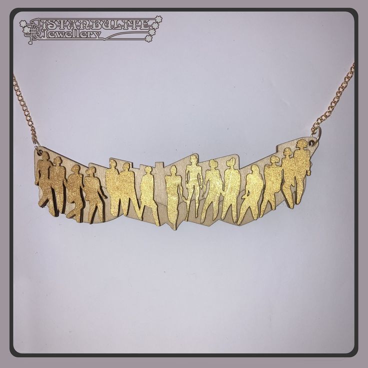 an image of a gold necklace that has people on it and is hanging from a chain