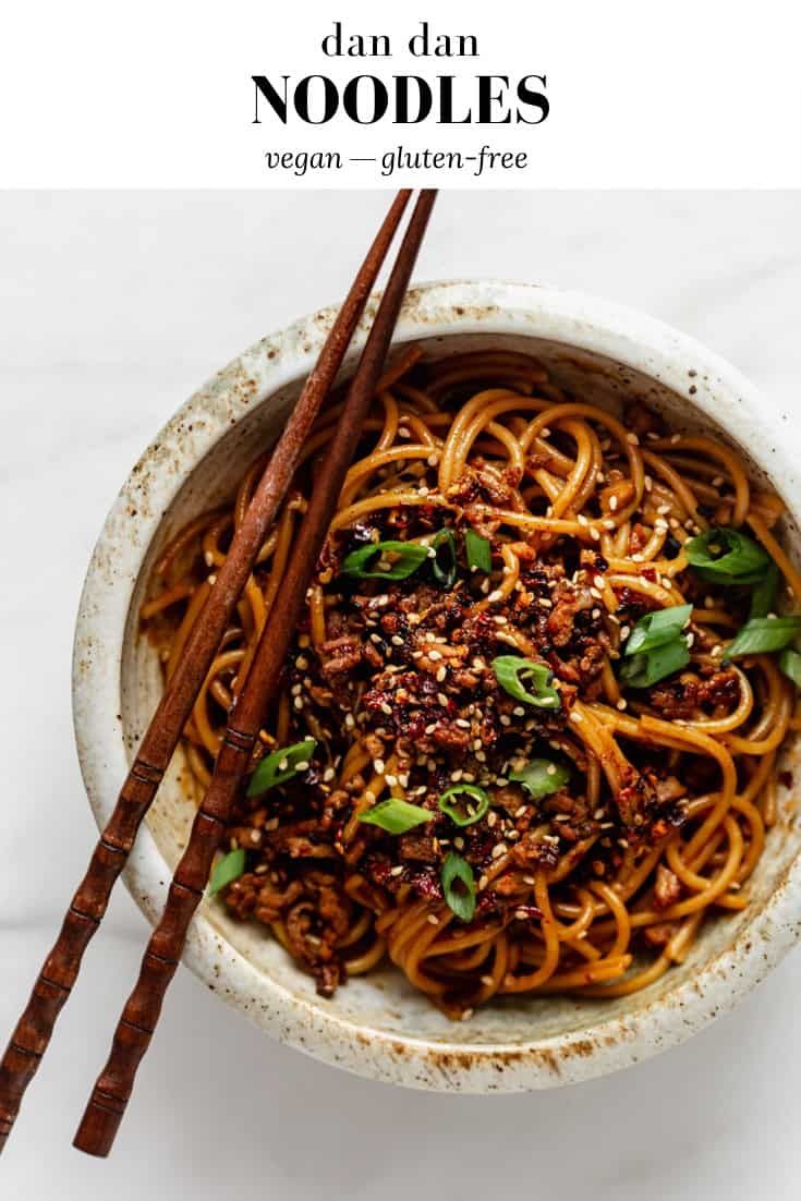 a bowl filled with noodles and chopsticks on top of a white countertop