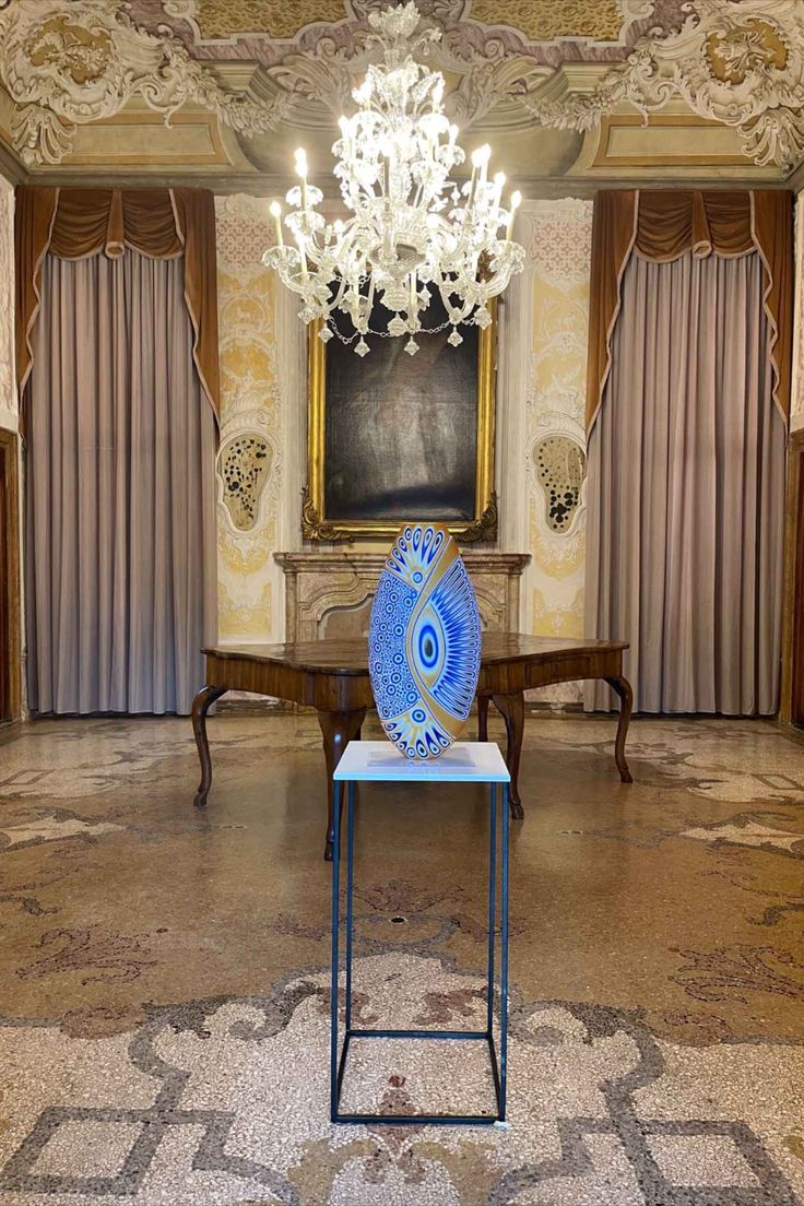 a blue vase sitting on top of a table in front of a chandelier