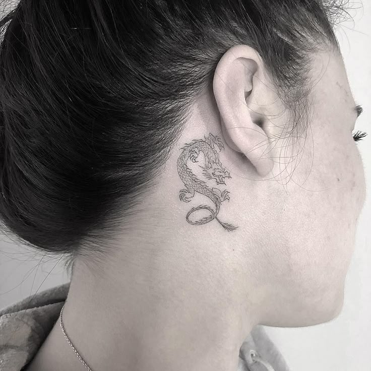 a woman with a small dragon tattoo on her left side behind the ear is a black and white photo