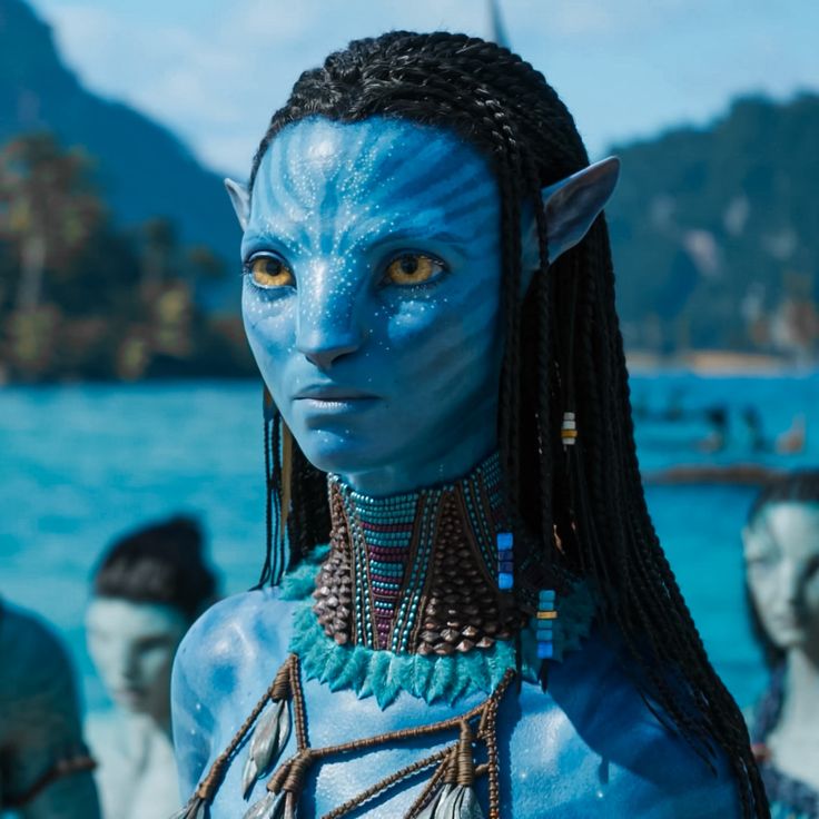 a woman with blue makeup and braids standing in front of the ocean, surrounded by other people