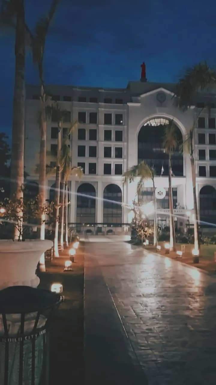 a large building lit up at night with palm trees