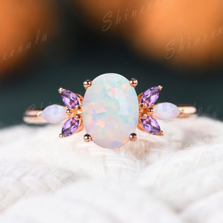 an opal and amethorate ring sitting on top of a white blanket