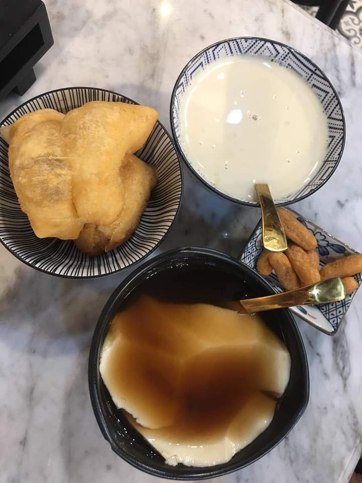 two bowls filled with food sitting on top of a table next to a cup of milk