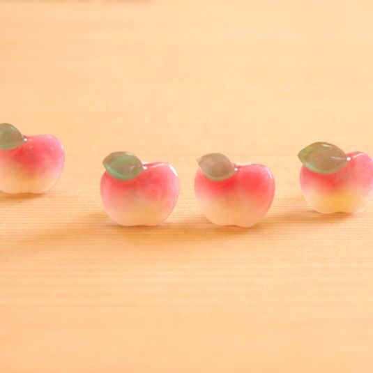 three small pink and green apples sitting on top of a wooden table next to each other