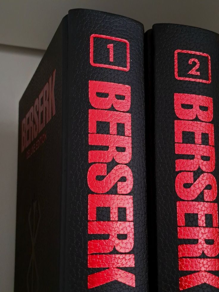 two black books with red lettering on them sitting next to each other in front of a white wall