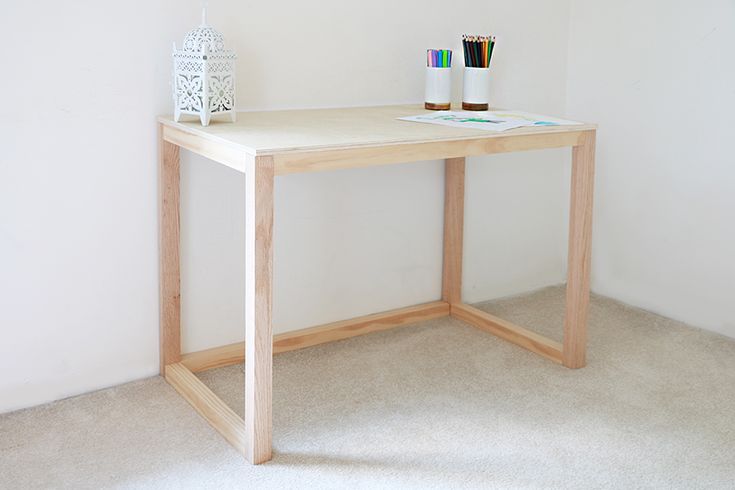 a wooden desk with two candles on it and a white vase sitting next to it