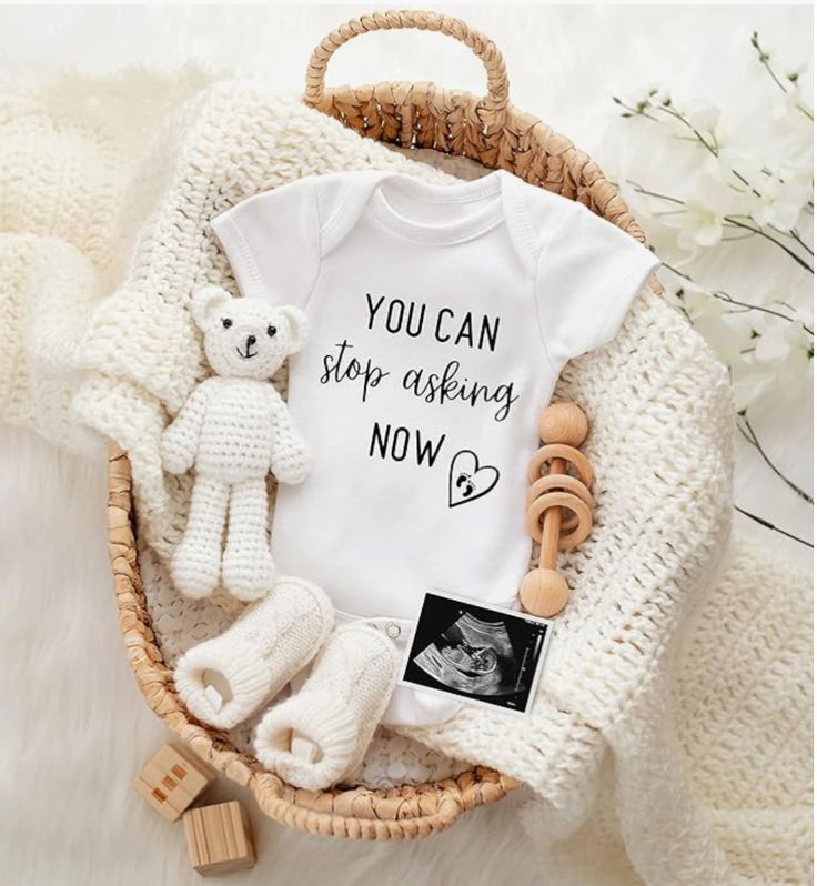 a basket filled with baby items including a t - shirt that says you can stop asking now