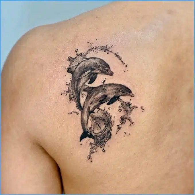 two dolphins on the back of a woman's shoulder