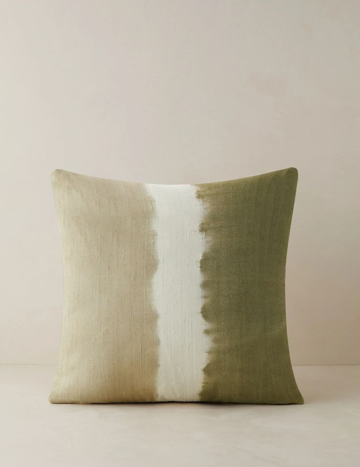 a green and white pillow sitting on top of a table next to a beige wall