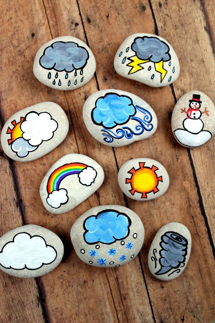 painted rocks with different weather symbols on them sitting on a wooden floor next to each other