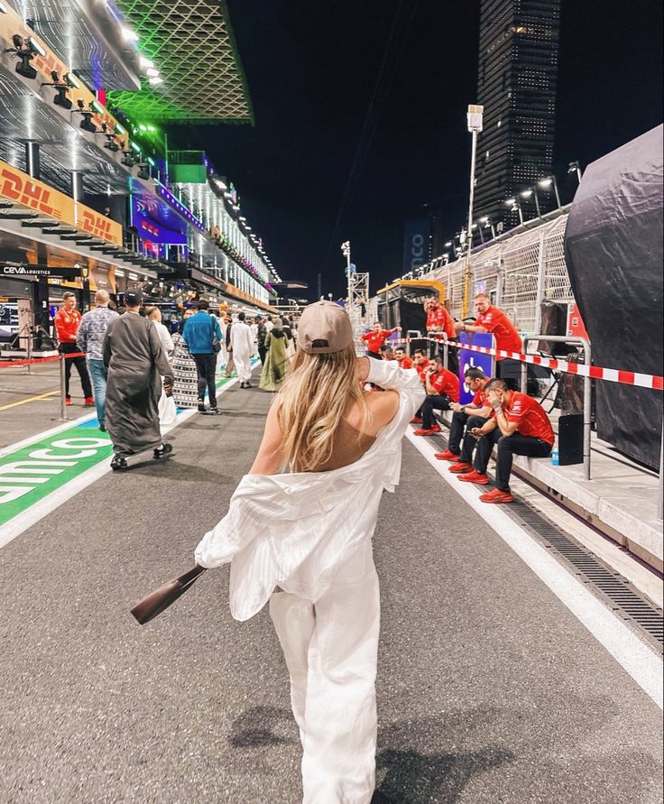 a woman in white is walking down the street with her baseball bat and other people