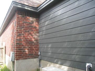 a bench sitting in front of a house next to a fence and grass covered yard