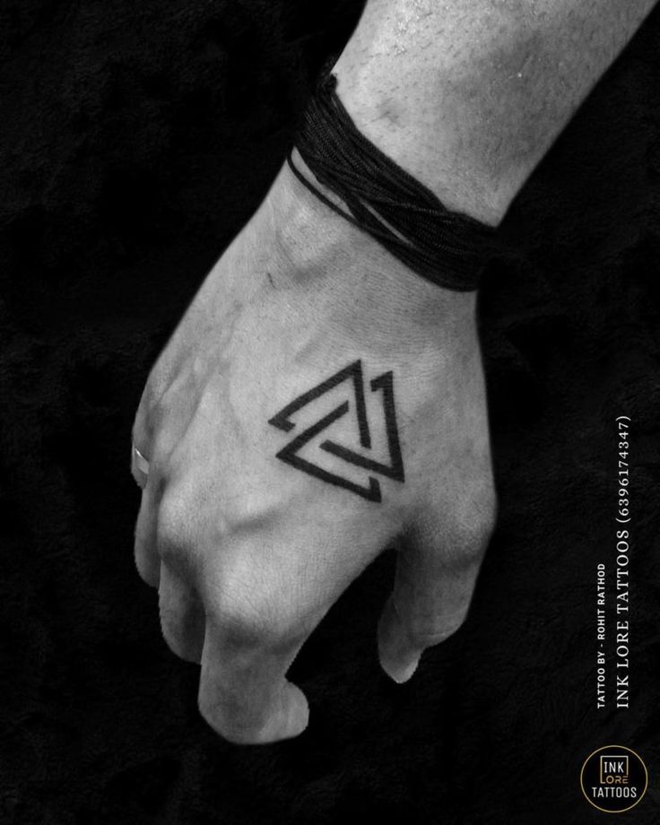 a black and white photo of a hand with a triangle tattoo on the left wrist