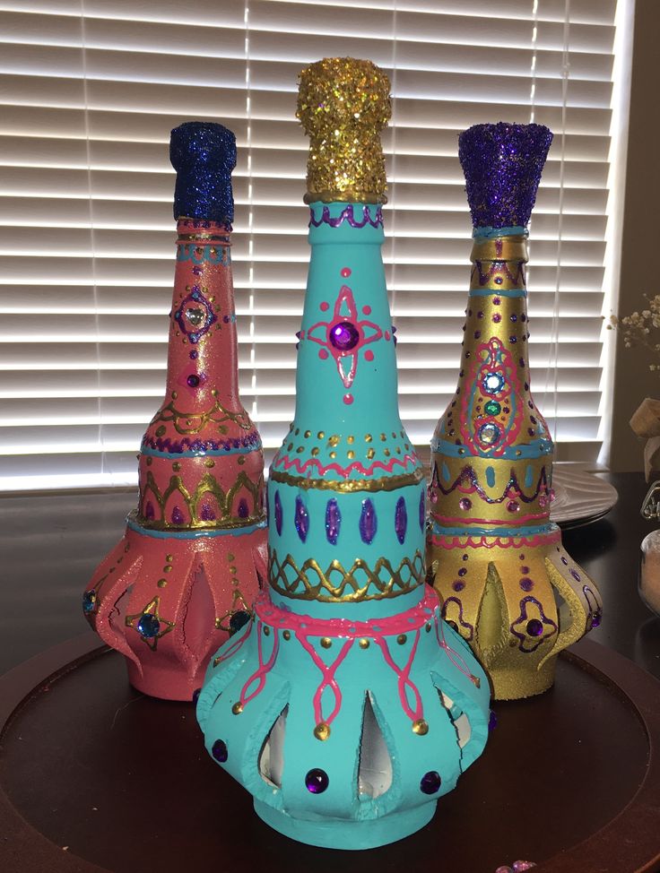 three colorful vases sitting on top of a wooden table next to a window with blinds