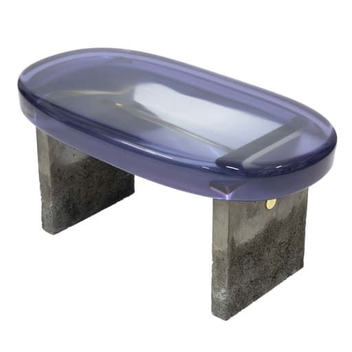 a purple glass bench sitting on top of cement block legs in front of a white background