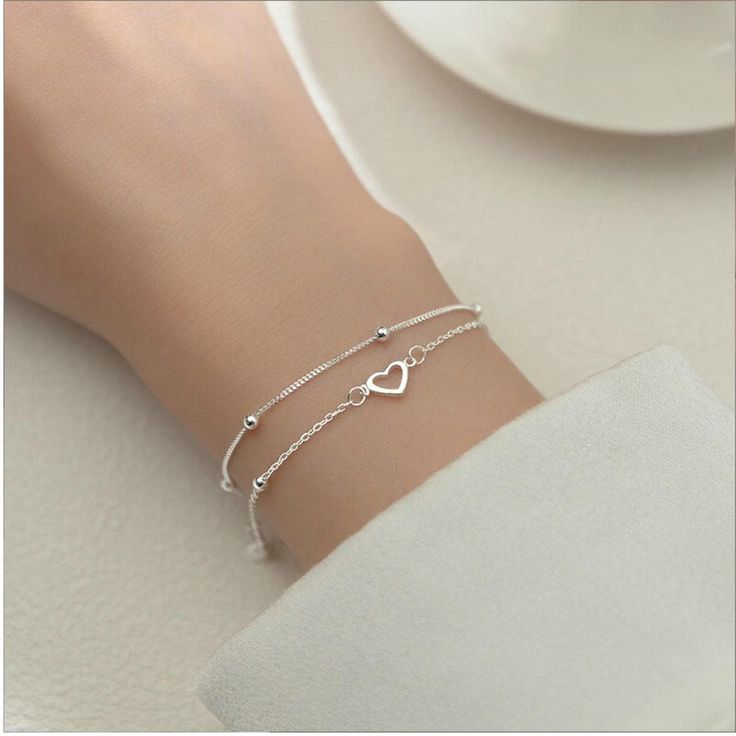 Dainty Heart Charm Beaded Bracelet for Women | 925 Sterling Silver | Double Layers | Adjustable Minimalist Love Jewelry Looking for the perfect blend of elegance and simplicity? This Dainty Heart Charm Beaded Bracelet is your next must-have accessory! Crafted from high-quality 925 sterling silver, this double-layered bracelet features two delicate heart charms and tiny, glimmering beads. Its minimalist design makes it incredibly versatile--whether you're dressing up for a special occasion or keeping it casual, this bracelet effortlessly complements any look. This bracelet is more than just a piece of jewelry; it's a statement of love and style. Wear it solo for a subtle sparkle or layer it with other pieces to create endless, unique combinations. It's not just a bracelet--it's a conversati Dainty Silver Jewellery, Silver Bracelet Aesthetic, Bead Bra, قلادات متدلية, Fashion Romantic, Gelang Manik-manik, Jewelry Classic, Silver Heart Bracelet, Romantic Jewelry