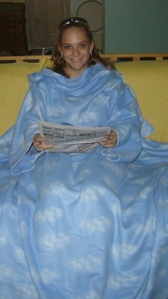 a woman wrapped in a blue blanket sitting on a yellow couch with her legs crossed