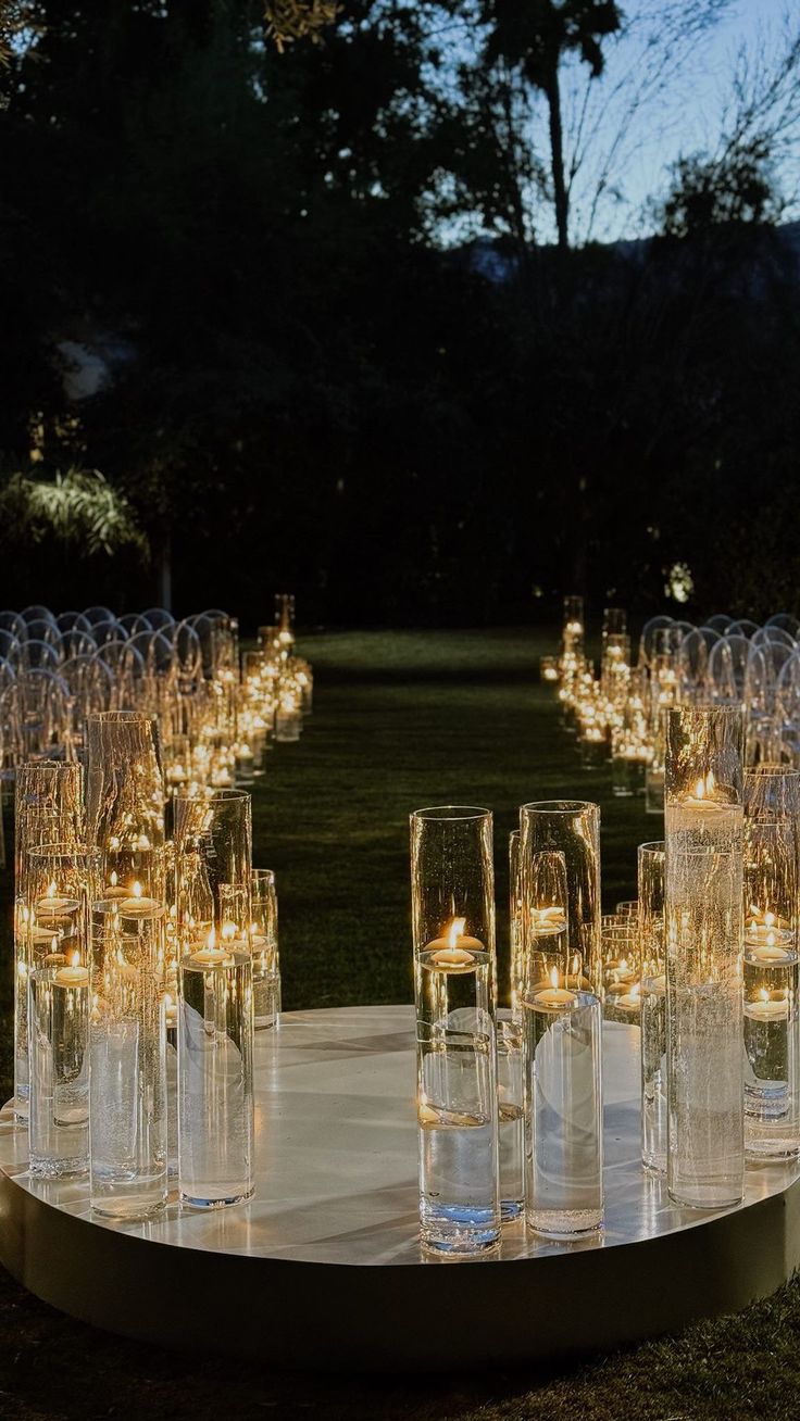 a table topped with lots of glasses filled with candles