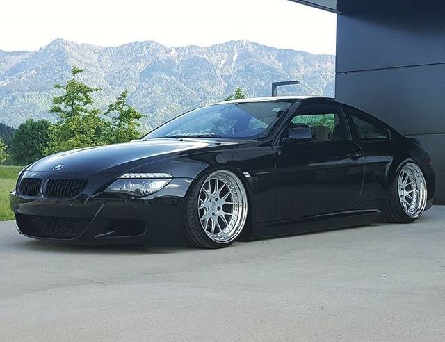 a black sports car parked in front of a building with mountains in the back ground