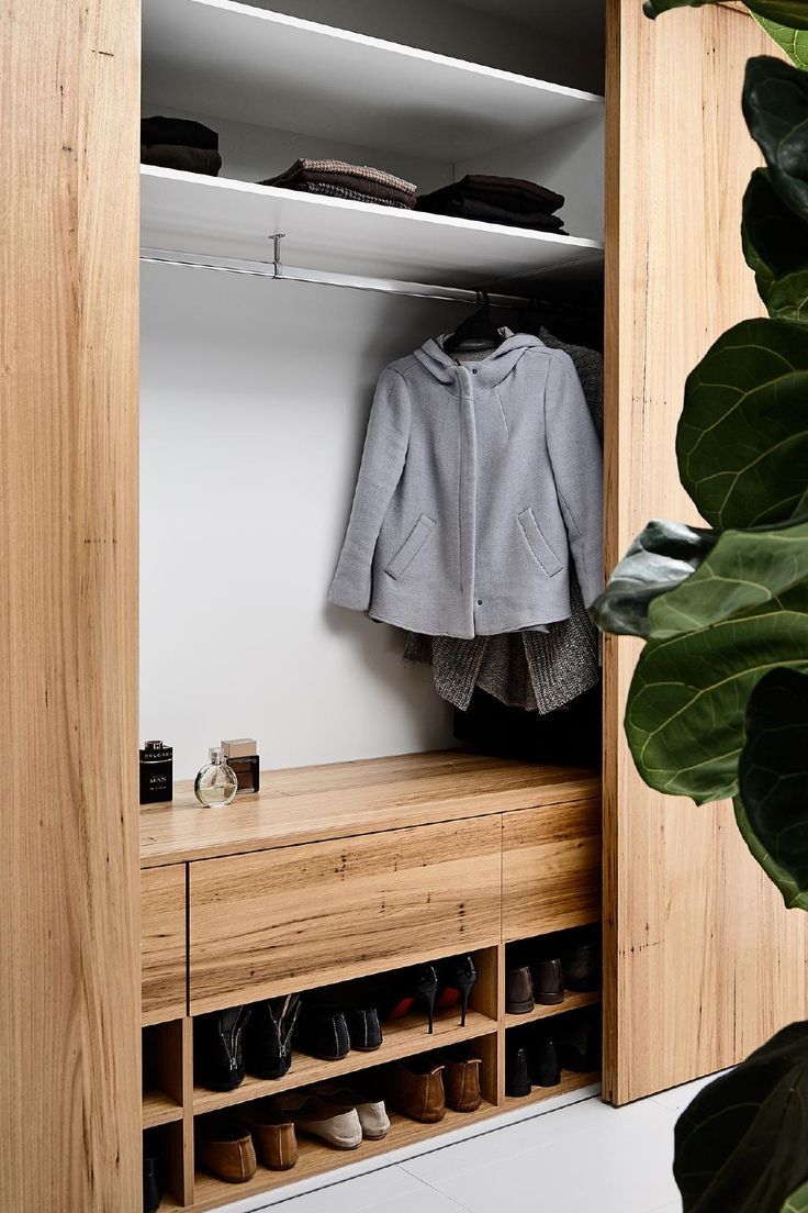 an open closet with shoes and coat hanging on the wall