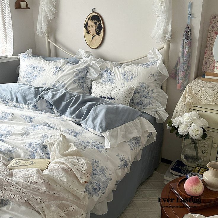 a bed with blue and white comforters in a bedroom next to a table with flowers on it