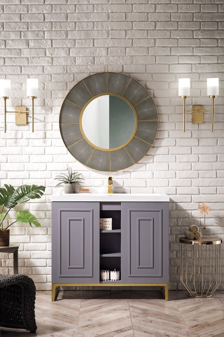 a white brick wall with a mirror above it and a gray cabinet in the middle