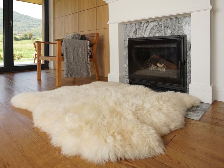 a large white sheepskin rug in front of a fireplace