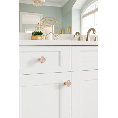 a bathroom with white cabinets and pink flowers on the drawer knobs in front of the sink