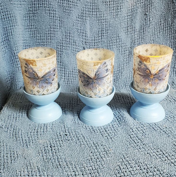 three blue candle holders with butterflies on them