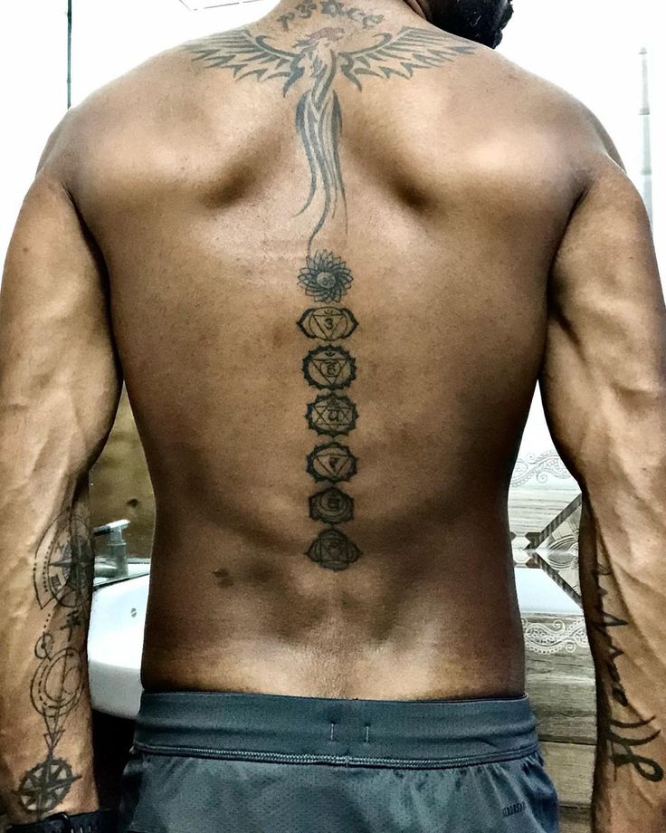 a man with tattoos on his back standing in front of a mirror