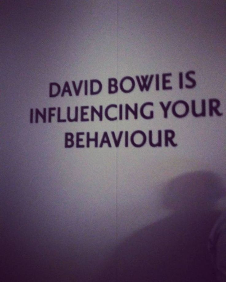 a man standing in front of a sign that says david bowlie is influenced by your behavior